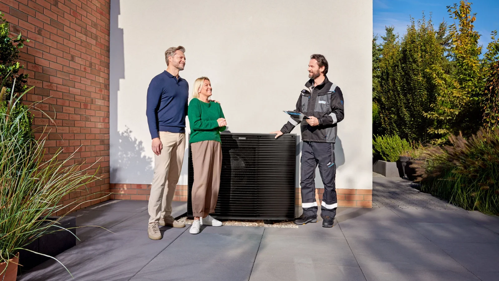 Majitelia domu pri konzultácii s odborníkom vedľa vonkajšej jednotky Daikin Altherma
